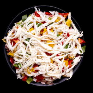 Alambre de res con queso Oaxaca y pimientos tricolor sobre plato negro y fondo oscuro