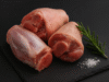 Codillo de cerdo crudo sobre fondo negro con sal de grano y romero fresco
