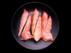 Manitas de cerdo crudas sobre fondo negro con plato negro