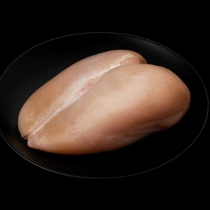 Pechuga de pollo crudas, sin piel ni hueso, sobre tabla de madera con hojas de romero y especias, fondo negro.