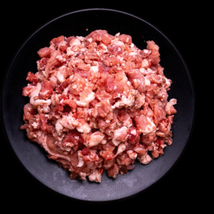 Suadero molido fresco sobre plato negro con especias y romero sobre fondo oscuro