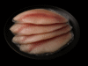 Filetes de tilapia congelados, colocados en un plato negro, listos para cocinar.